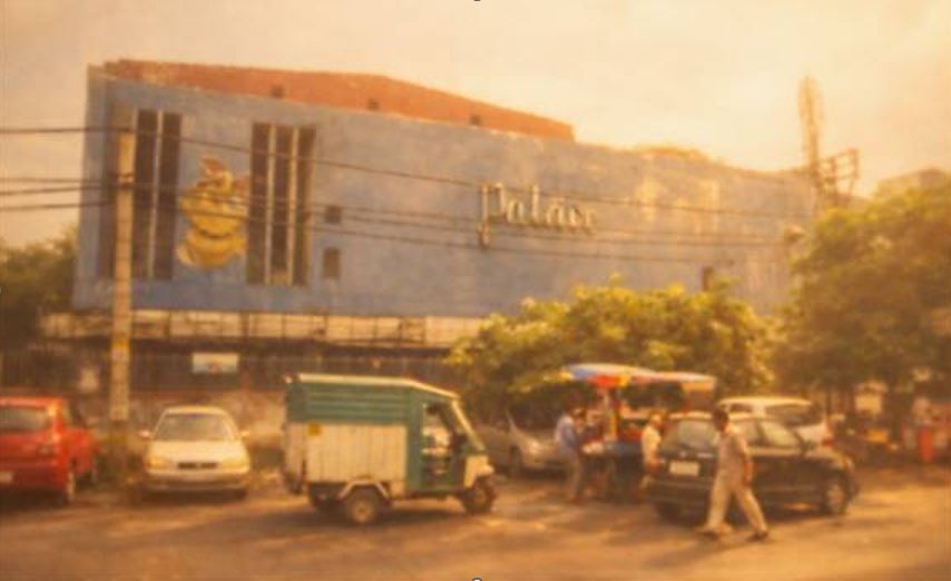 Roshanara Road in Delhi: a cinema building, parked cars and an auto rickshaw